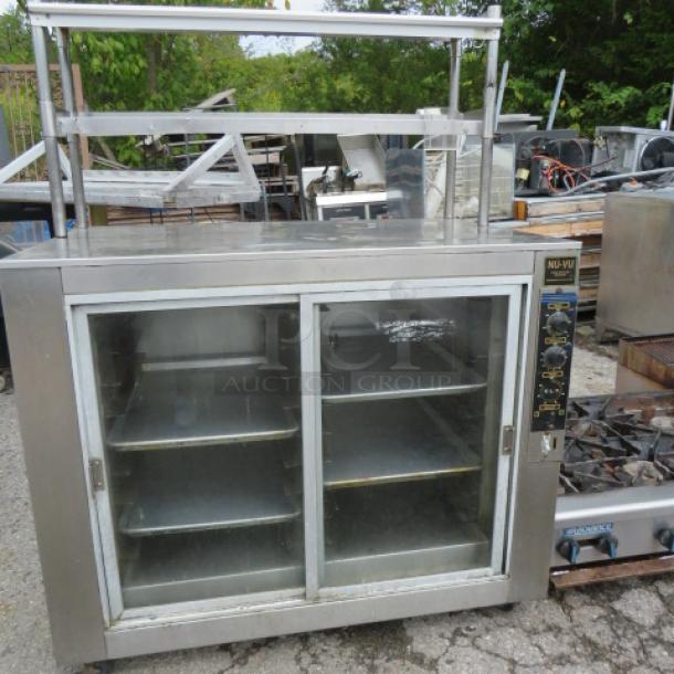 NUVU heated holding cabinet, 48x31x64, with two glass sliding doors, stainless steel shelves, and casters.