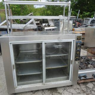 NUVU heated holding cabinet, 48x31x64, with two glass sliding doors, stainless steel shelves, and casters.
