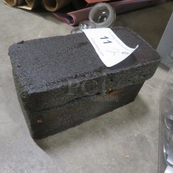 Griddle Brick 2XBID, textured surface, used for cleaning grill surfaces. Auction tag showing lot number. Good condition.