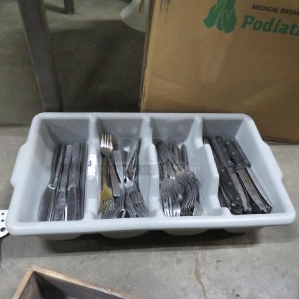 Gray flatware holder containing assorted flatware including forks, knives, and spoons. Used condition.