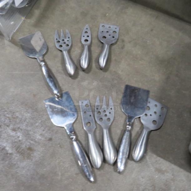 One lot of 9 stainless steel cheese serving tools, including slicers and forks, in good condition.