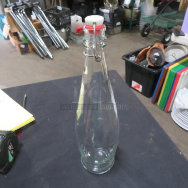 Clear glass water bottle with hinged lid, rubber seal, and metal clasp. Item 4XBID. Excellent condition.