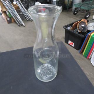 Clear glass carafe with wide neck and round base, in excellent condition. Ideal for serving beverages. No visible markings.
