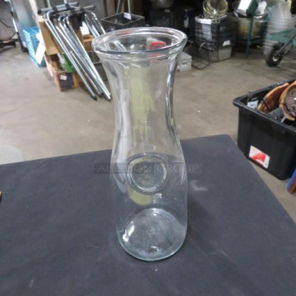 Clear glass small carafe with a wide mouth and narrow neck. Used condition, no visible markings.