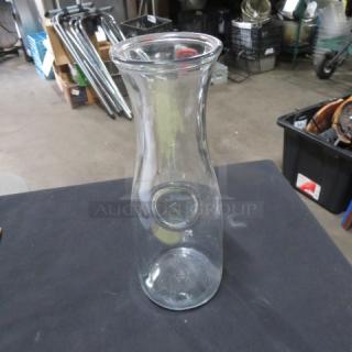 Clear glass small carafe with a wide mouth and narrow neck. Used condition, no visible markings.