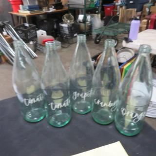 Clear glass bar juice bottles, set of five, each labeled with different fruit names. Used condition. No visible damage.