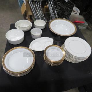 Assorted gold-edged dishes set on a table, featuring various sizes, pristine condition, elegant design.