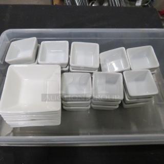 Large lot of white ceramic sauce holders, various sizes, stacked neatly in a transparent container.