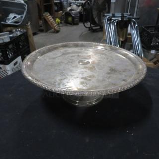 12-inch round silver plate cake stand with ornate edge design, polished finish, and slight tarnishing. Ideal for elegant displays.