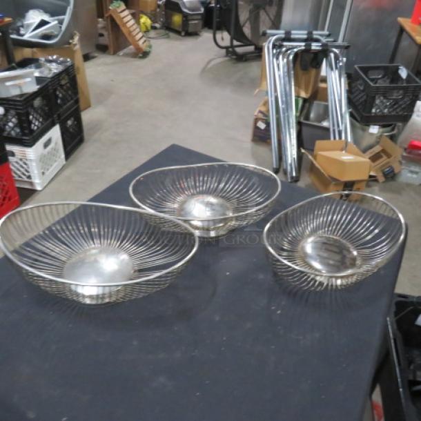 Set of three wire baskets with a silver finish, round shape, open design, good condition, ideal for decorative or functional use.