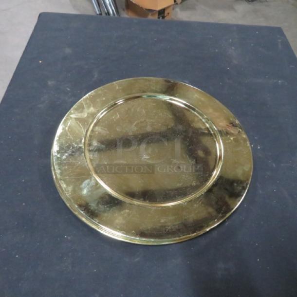 Gold charger plate with a reflective surface, showing signs of wear. Item code 5XBID.