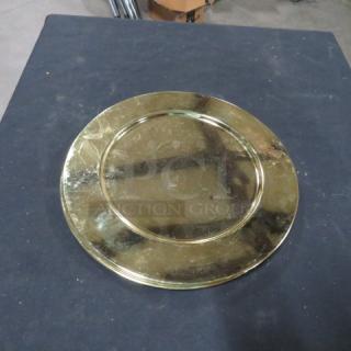Gold charger plate with a reflective surface, showing signs of wear. Item code 5XBID.
