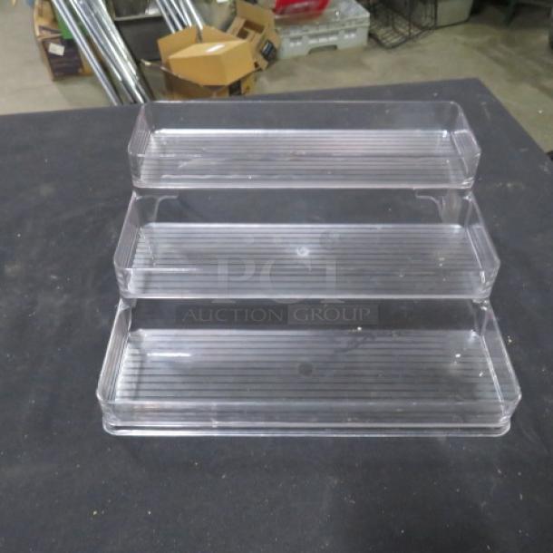 Clear 3 tier poly shelf, 4XBID model, in excellent condition. Each tier features a ribbed surface for stability. Ideal for organizing small items.