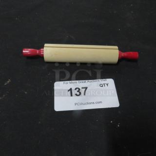 Wooden rolling pin with red handles on a black surface. Auction label "137 QTY" visible.