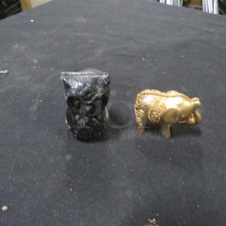 One black owl and one gold elephant place card holder on a black surface.