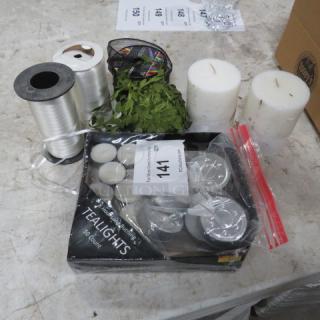A lot containing spools of white ribbon, two pillar candles, a pack of 50 tealights, and a spool of green ribbon.