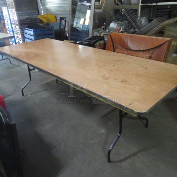 Wooden folding table, 96x36x30 inches, with metal legs. Light wood finish, slight wear, ideal for events or gatherings.