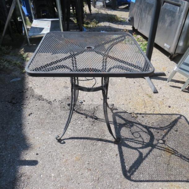 Black metal patio table, 28x28x29 inches, featuring a mesh top and decorative curved legs, in good condition.