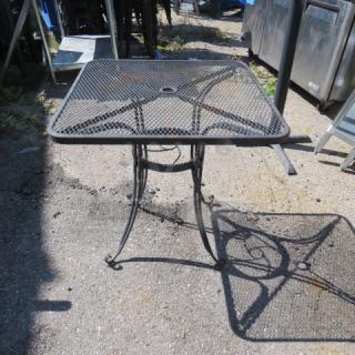 Black metal patio table, 28x28x29 inches, featuring a mesh top and decorative curved legs, in good condition.