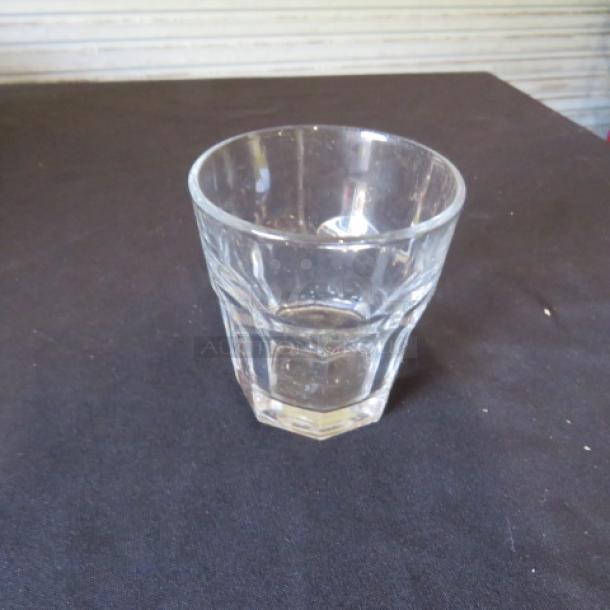 Clear glass rocks glass, model 10XBID, with faceted design. Appears in good condition on a dark surface.