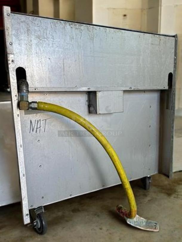 Commercial 6-burner gas range with oven, natural gas, fully tested, operational, yellow hose attached, back view.