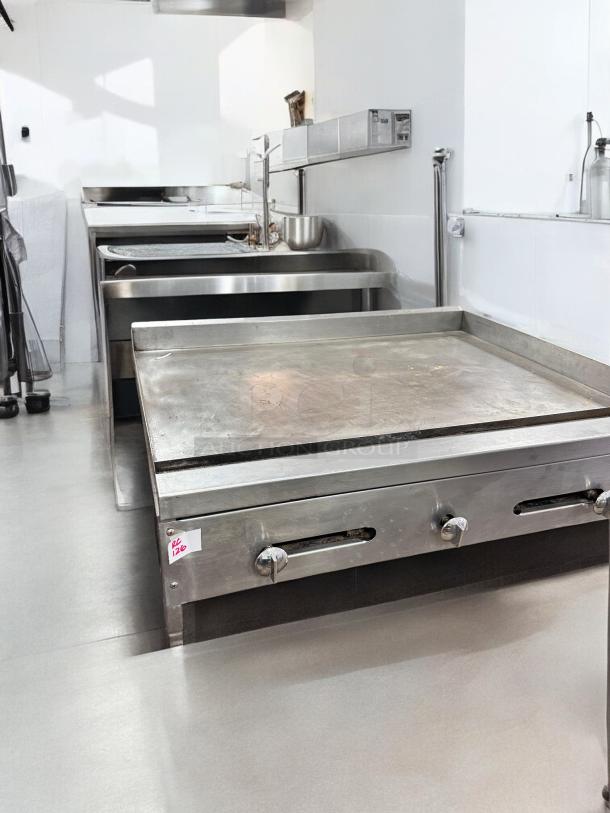 Commercial-grade 36" stainless steel flat top gas griddle in superb condition, fully tested and working, with control knobs.