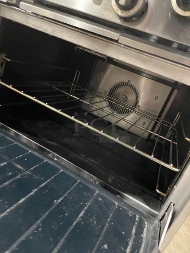 U.S. Range 10-burner stainless steel gas range with double oven, backsplash, wire rack, and adjustable legs.