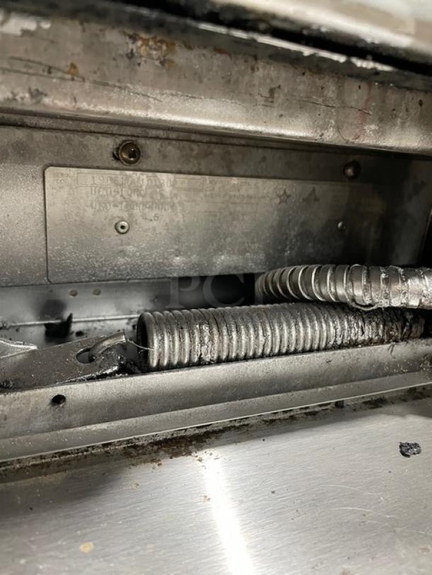Close-up view of the U.S. Range commercial stainless steel gas range, showing wiring and metal details.