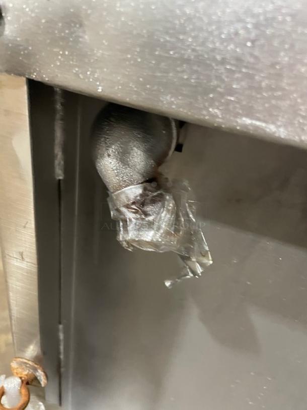 Jade Range gas fitting with visible pipe and tape, part of a 36" stainless steel flat top range/oven on casters.
