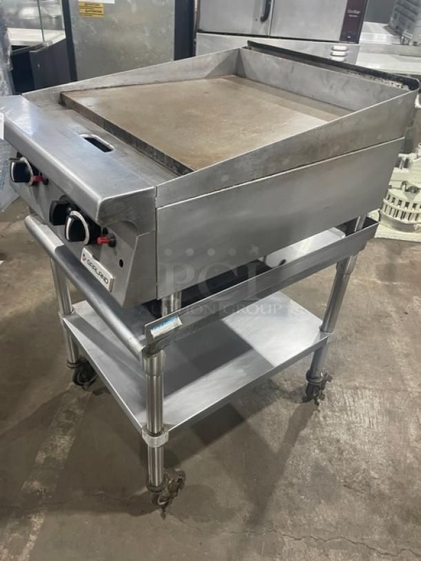 Garland stainless steel natural gas-powered griddle with thermostatic control, back, and side splash, on legs with BK Resource undershelf stand on casters.