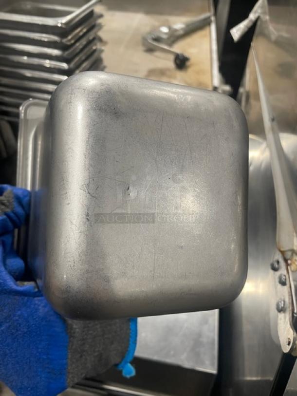 Stainless steel hotel steamtable pan, shows light wear, durable construction, ideal for commercial use. Stack of pans visible.