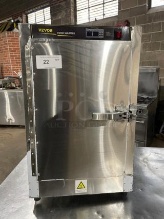 Vevor stainless steel countertop food warmer with digital controls, on legs. Features brand label and a safety warning tag.