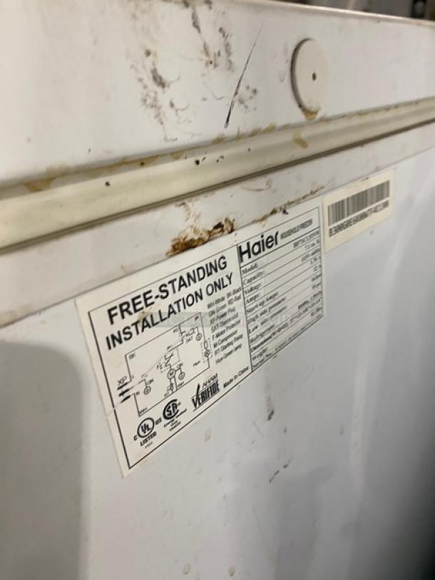 Haier Commercial Chest Freezer, model HE71CL53NW, with lift-up lid. Freestanding, 115V, serial number visible. Some surface wear.