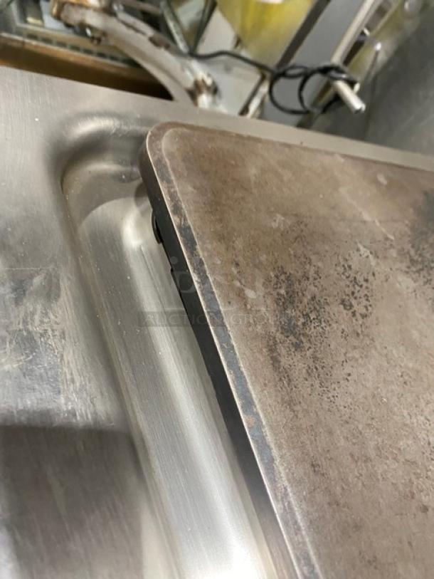 Electrolux Thermaline stainless steel flat top grill, natural gas-powered, with enclosed open base, visible wear on surface.