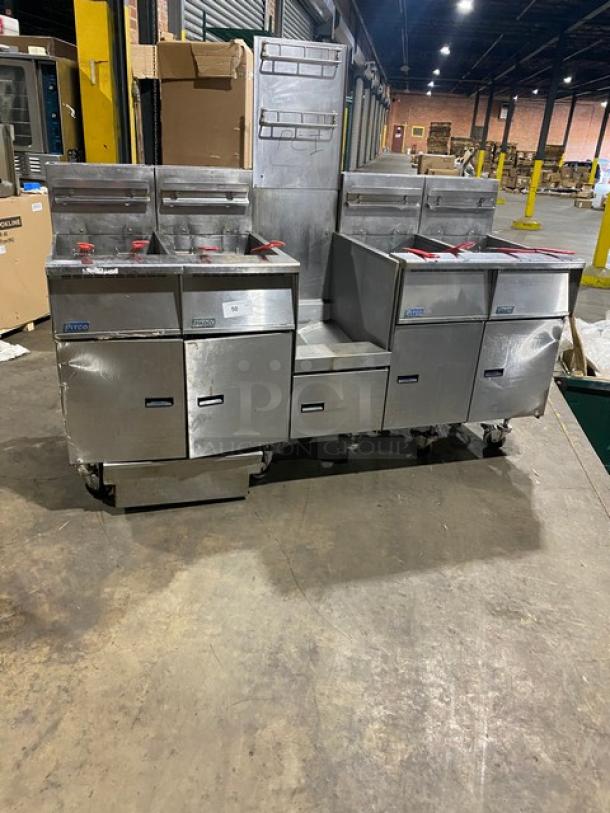 Pitco FGSGH50 stainless steel 4-bay fryer system on casters with center basket hanger, backsplash, baskets, and oil filter.