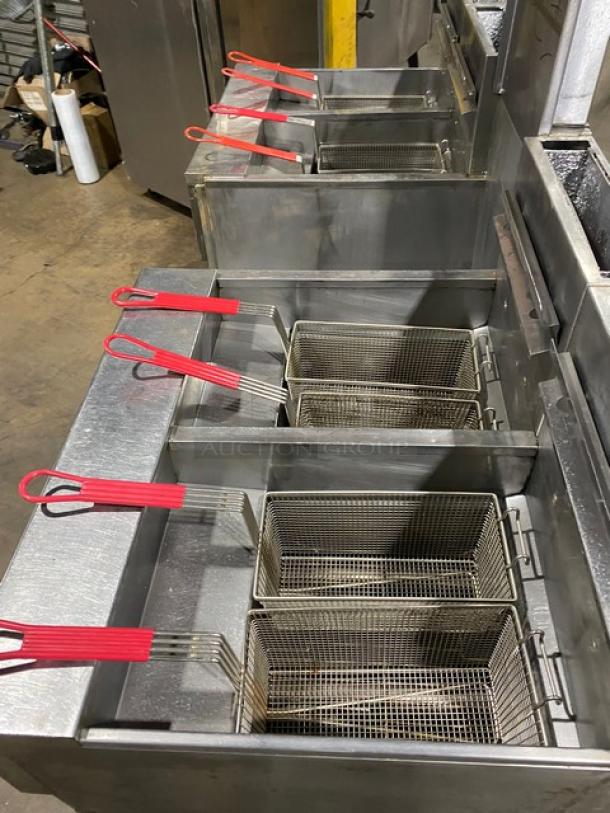 Pitco FGSGH50 4-bay stainless steel fryer system with basket hanger, backsplash, oil filter, and casters. Model G13JE049284.