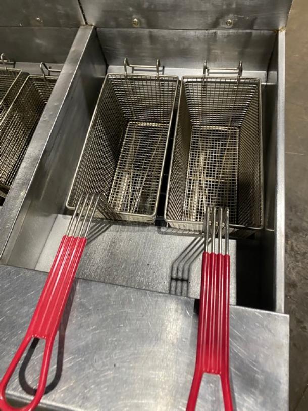 Pitco FGSGH50 4-bay stainless steel deep fat fryer system with basket hangers, red-handled fry baskets, and oil filter.