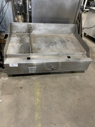 Woodstone 48" stainless steel countertop split-top plancha griddle with natural gas power, back and side splash, on legs.