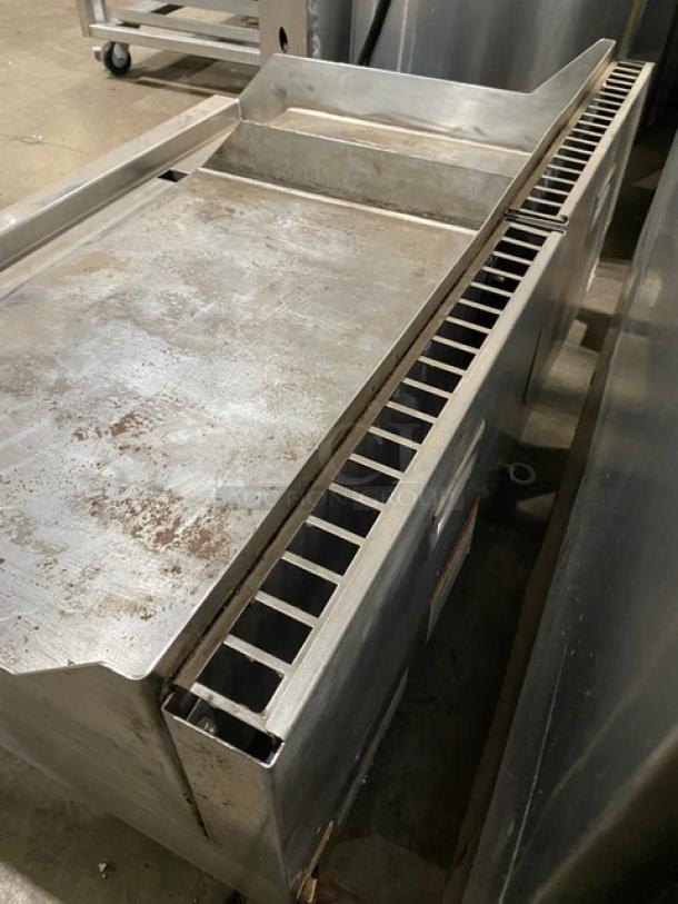Woodstone 48" stainless steel split-top plancha griddle with back and side splash, on legs. Natural gas powered. Moderate wear.