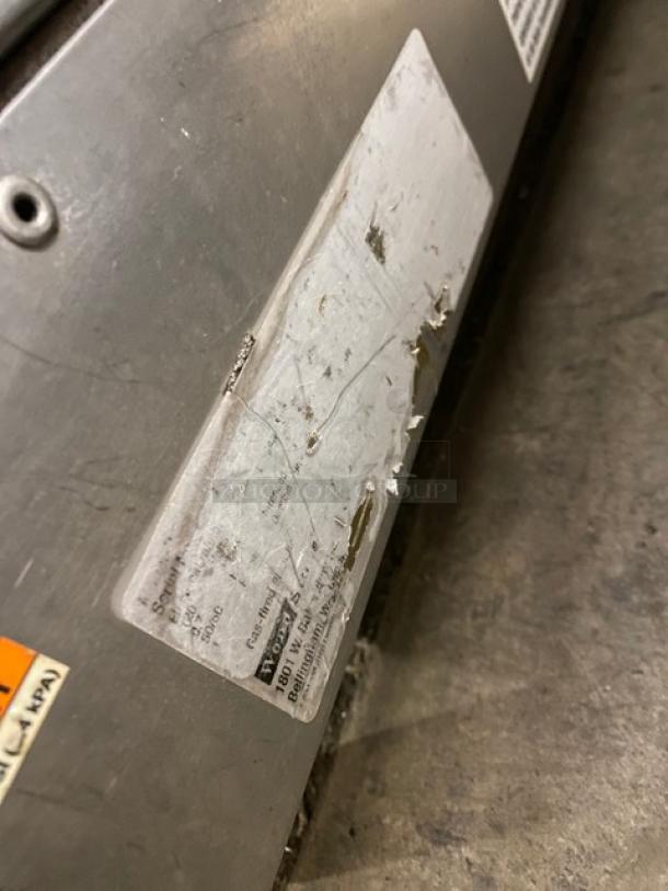 Woodstone commercial stainless steel 48" gas griddle with split-top, back, and side splash. Worn label visible.