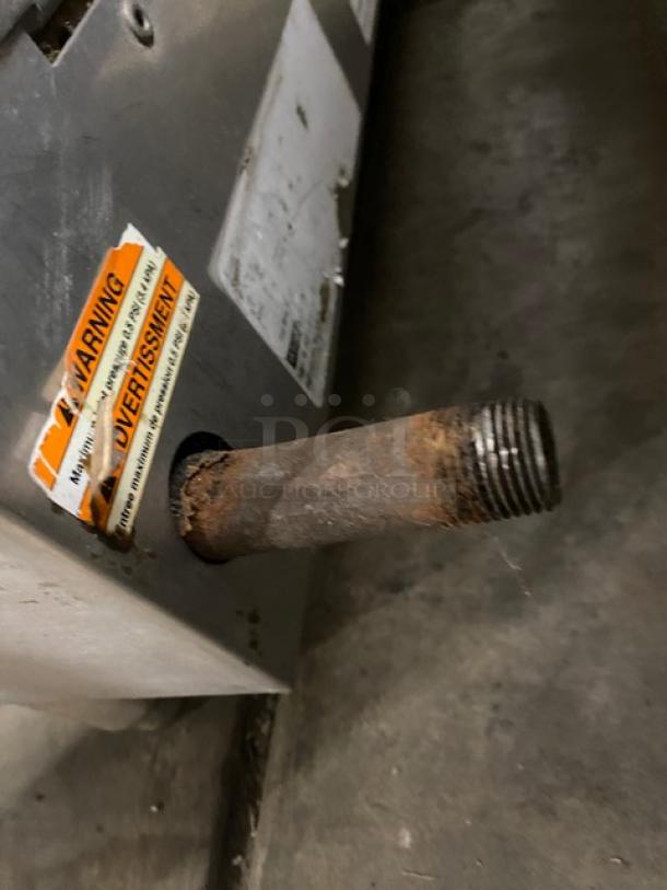 Woodstone commercial stainless steel natural gas griddle side view, showing rusted pipe and warning label.