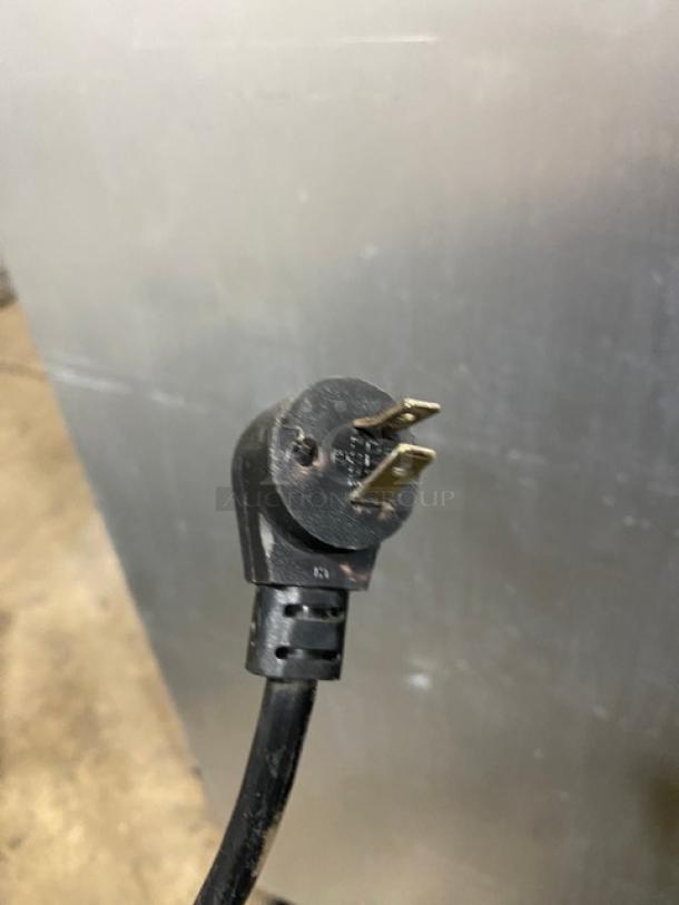 Close-up of a power plug from a Delfield refrigerated worktop table. Model UC4048-STAR. Black casing, two-prong plug.