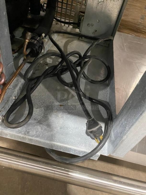 Stainless steel food prep table underside showing electrical cord and metal structure, indicating durability and utility.