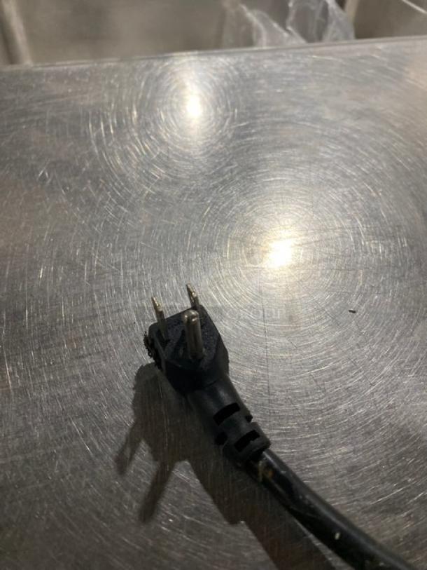 Close-up of a power plug on a stainless steel surface, possibly of an Atosa 2-door bar cooler, model SBB48GGR.