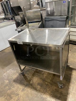 Commercial stainless steel worktop/prep table with double foldable shelf, enclosed base, and casters; minor surface marks visible.