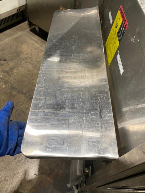 Commercial stainless steel prep table with enclosed base, double foldable shelf, and casters; visible wear, safety warnings.
