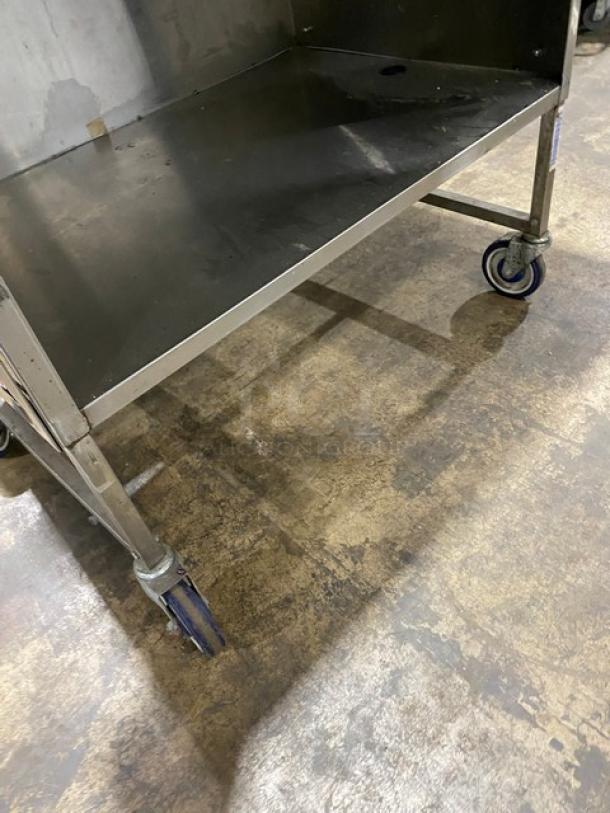 Commercial stainless steel prep table with enclosed base, double foldable shelf, and casters. Excellent condition.