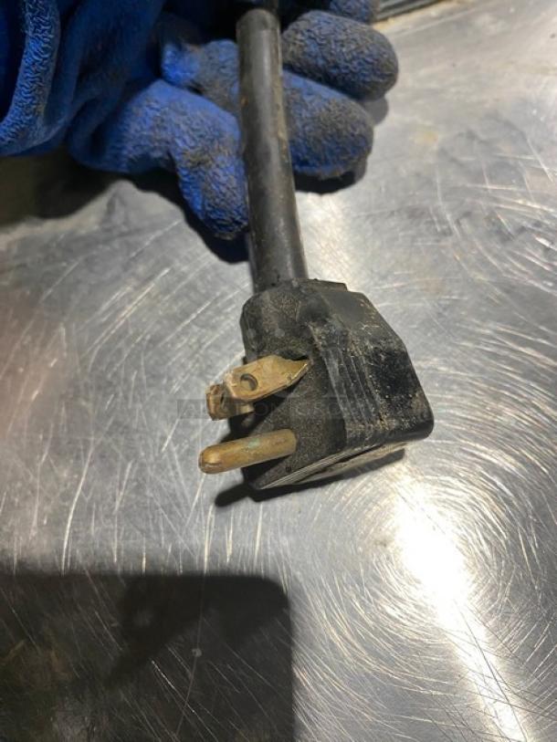 Damaged electrical plug of True Model TSSU-27-12M-B refrigerated prep table, pictured on stainless steel surface.