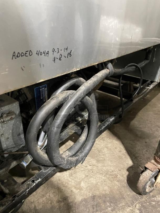 True T-49F commercial stainless steel 2-door reach-in freezer on casters, shown with poly-coated wired rack and visible handwritten service dates.