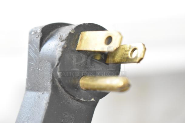 Close-up of a power plug for the Beverage Air UCR48A stainless steel commercial cooler, showing prongs and wear marks.